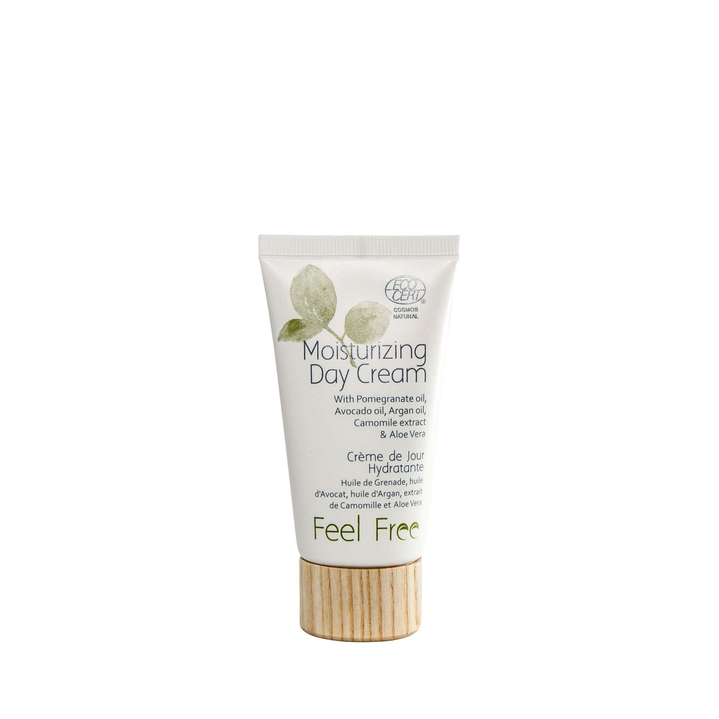 A white tube of Feel Free Moisturizing Day Cream with a cylindrical wooden cap and a matte surface finish. The front displays green leaf graphics and printed text listing ingredients including pomegranate oil, avocado oil, and aloe vera. The product name is in sans-serif font. Neutral background with no visible people or hands. A white tube of Feel Free Moisturizing Day Cream with a wooden cap, featuring green leaf artwork and text highlighting ingredients such as pomegranate oil, avocado oil, and soothing