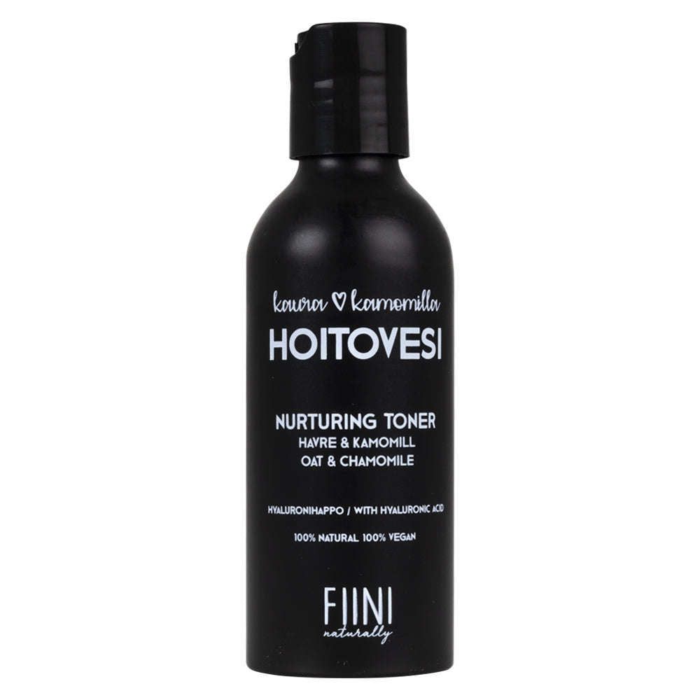 Fiini Naturally Kaura-Kamomilla Hoitovesi; musta pullo mattapintaisena, sylinterinmuotoinen pumppuannostelijalla; valkoisessa etiketissä selkeä groteskiteksti "HOITOVESI Nurturing Toner by FIINI Naturally", mainiten vegaaniset ainesosat kuten kauran ja kamomillan sekä kosteuttavan hyaluronihapon; neutraali tausta, ei ihmisiä kuvassa.