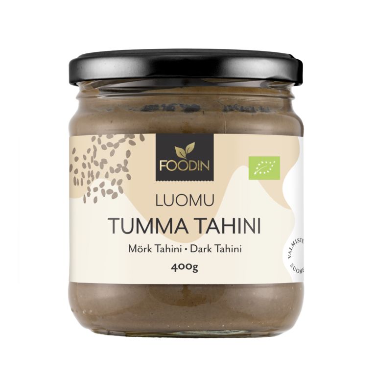 Foodin Luomu Tahini Tumma -lasipurkki, 400 g; kiiltävä musta muovinen kierrekorkki; sylinterimäinen purkki, jonka mattapintaisessa beigessä etiketissä on ruskeita geometrisia kuvioita; etiketissä monikielistä tekstiä lihavoidulla tekstausvapaalla kirjasimella sekä yksinkertaisia siemenkuvituksia; kuvattu vaaleaa yksiväristä taustaa vasten.