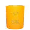 A bright orange candle in a clear glass cylindrical jar with a glossy finish, labeled JOIK HOME & SPA in black sans-serif font. The label is rectangular and placed on the front of the jar. The background is plain white, and no people or hands are present. The shot is a product-focused, straight-on view.