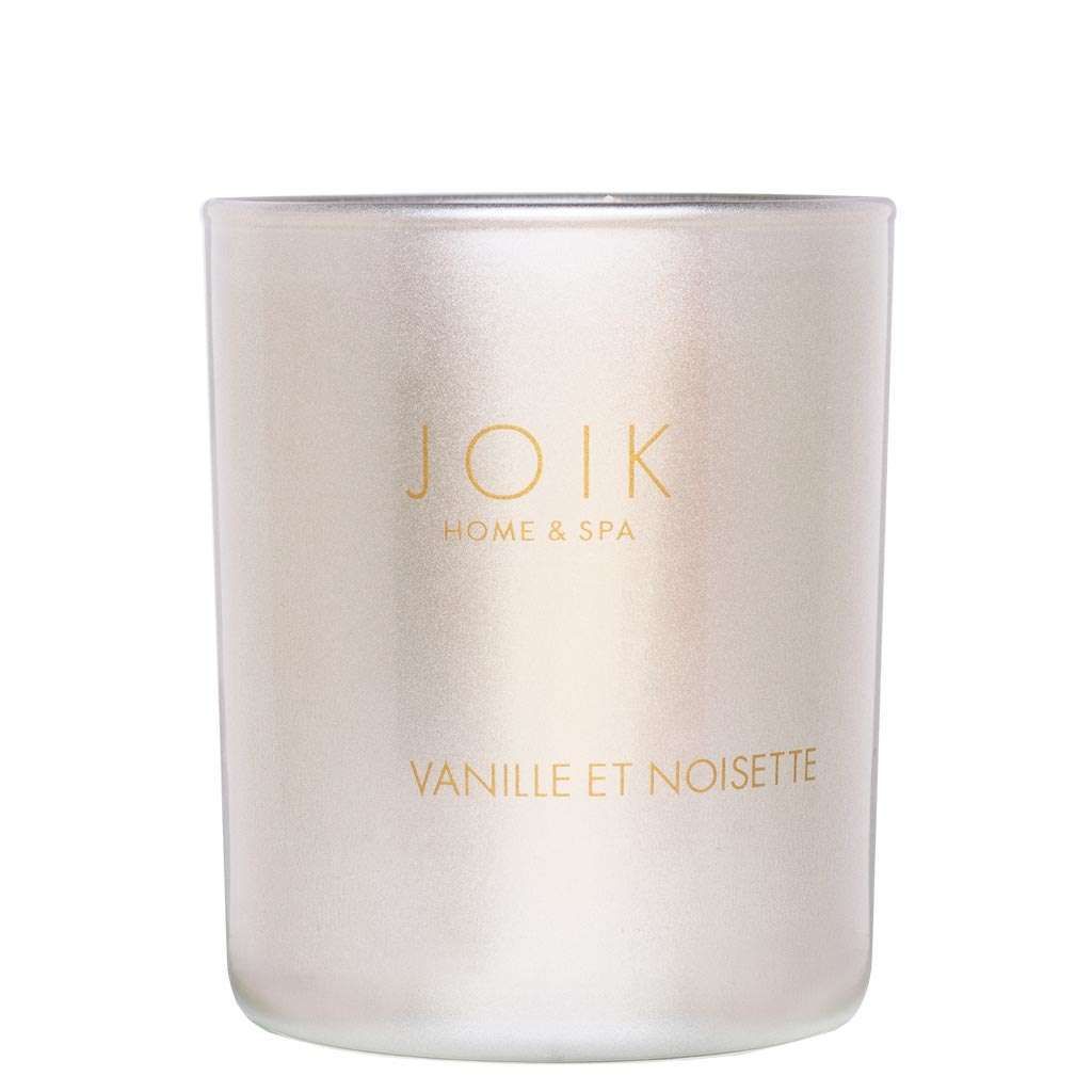 A frosted glass candle with gold text reading JOIK HOME & SPA and VANILLE ET NOISETTE on the front. Cylindrical shape, matte finish. Gold sans-serif typography printed directly on the glass surface. No visible lid or outer packaging. Neutral, seamless background; product is pictured alone in a straightforward studio shot.