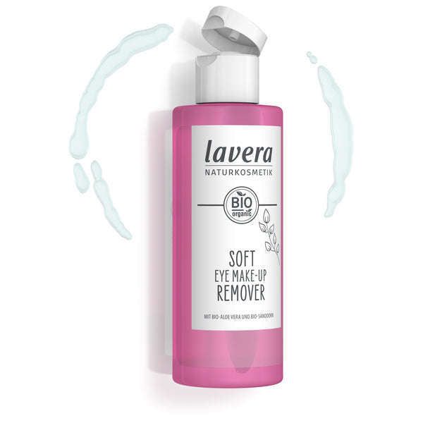 Lavera Soft Eye Silmämeikinpoistoaine; vaaleanpunainen ja valkoinen muovipullo Lavera Soft Eye Make-Up Remover -tuotetta valkoisella läppäkorkilla; pullo sylinterinmuotoinen sileän mattapintaisena; sinistä nestettä pirskeinä ympäröi tuotetta pelkistetyllä taustalla; etiketissä selkeä groteskikirjasin ja maininta luomualoe verasta sekä hellävaraisesta puhdistuksesta; ei ihmisiä tai käsiä kuvassa.