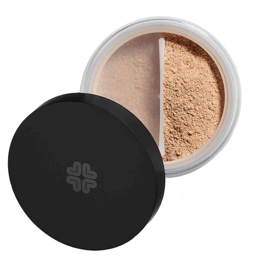 An open container of loose face powder with a black, matte-finish round lid is shown; the transparent plastic base reveals beige powder inside, separated by a rigid plastic sifter grid. No visible typography or labels. The surface is smooth and unembellished. Product sits on a plain white studio background with no people or hands visible in the frame. An open container of loose face powder with a black lid, showing the beige powder inside divided by a plastic separator for easy application.