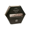 Luonkos Complete Facial Oil Cleansing Cake For Men; kuusikulmainen musta rasia hopeanvärisin korostuksin ja minimalistisella designilla valkoista taustaa vasten; rasia mattamusta, hopeanvärinen yksityiskohta etupinnalla, suorat reunat ja terävät kulmat; yksinkertaista groteskitekstiä; ei ihmisiä tai käsiä; tuote keskitetty kuvassa, kuvattu suoraan edestä.