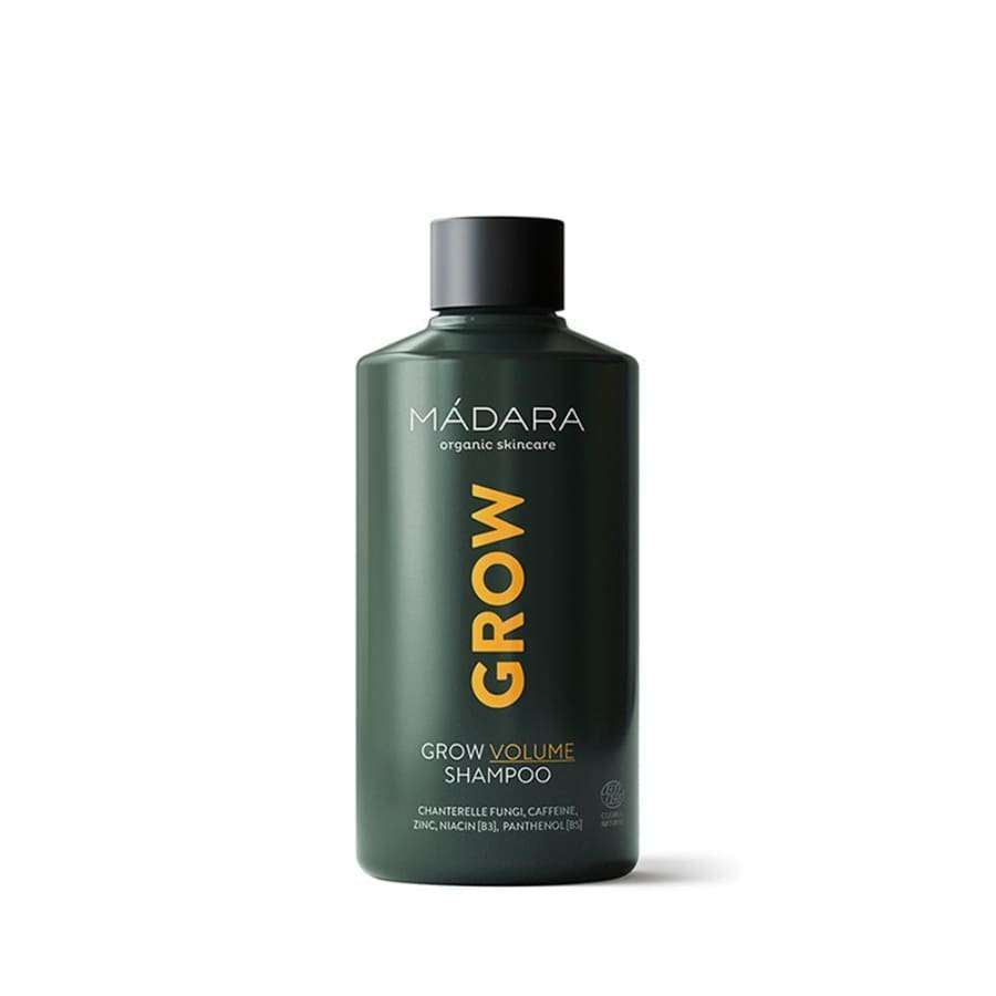 Mádara Grow Volume Shampoo -pullo, tummanvihreä sylinterimäinen muovipullo mattapinnalla; etiketissä oranssia ja valkoista tekstiä selkeällä modernilla tekstausvapaalla typografialla; pullo korkillinen, ei ihmisiä tai käsiä näkyvissä; tausta valkoinen ja tasaisesti valaistu, korostaen pakkauksen eloisaa ulkoasua.