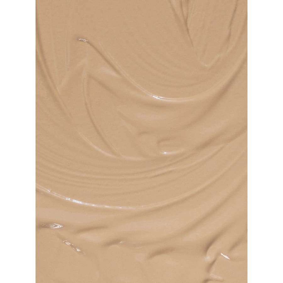 MÁDARA The Concealer, sävy Honey; sileä, beigenvärinen mineraalimeikkivoide levitettynä tasaisesti, pehmein kiehkuroin ja hienovaraisin tekstuurikuvioin; ei pakkausta, brändimerkintöjä tai tekstiä; matta pinta; lähikuva ilman taustaelementtejä, ihmisiä tai muita esineitä.