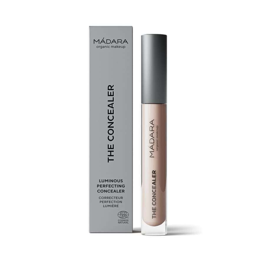 MÁDARA The Concealer, Luminous Perfecting Concealer, luomu, sävy Latte; putkilo harmaan rasian vieressä, molemmissa tuotenimi ja sertifiointilogot; putkilo lieriömäinen, mattaharmaa, minimalistinen muotoilu; rasia harmaa, mattapintainen, moderni groteskiteksti; vaalea tausta, ei ihmisiä.