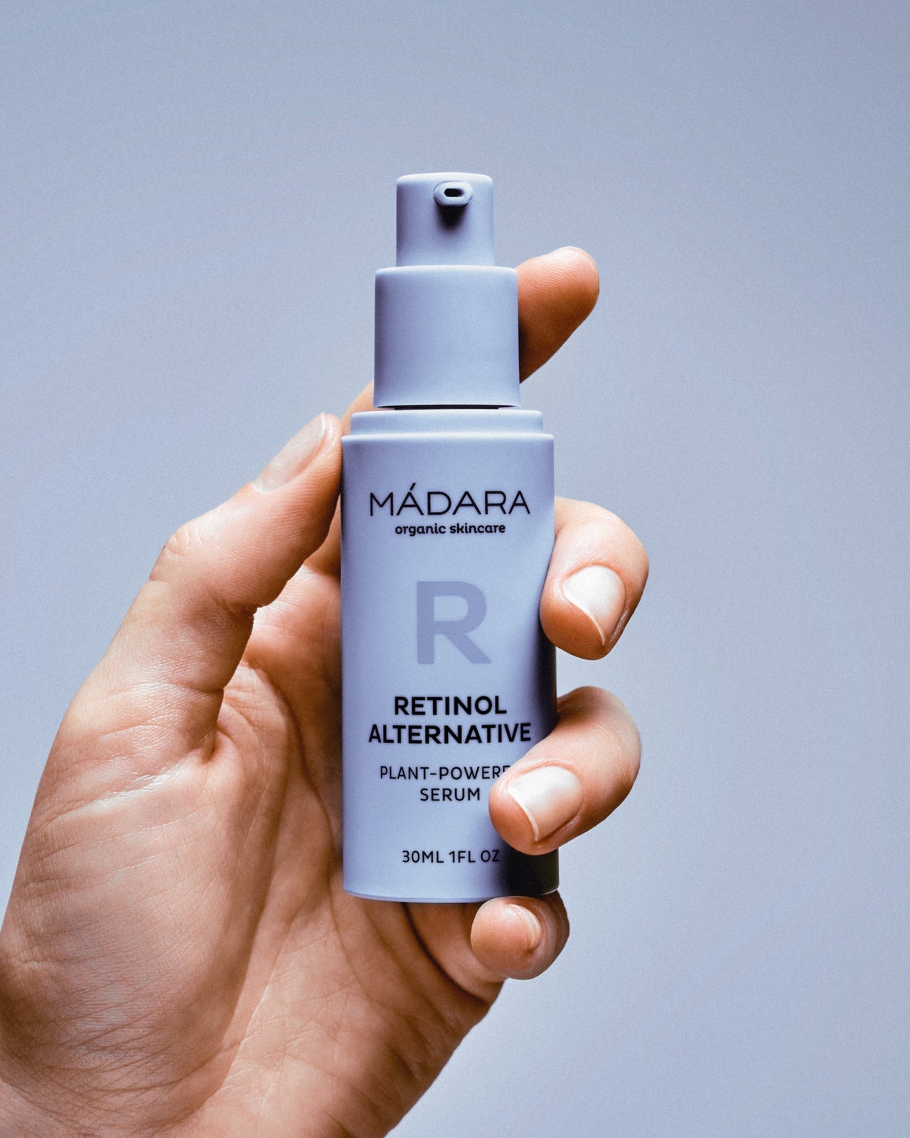 Madara Time Miracle Botanic Retinol Serum; pumppupullo kädessä sinistä taustaa vasten