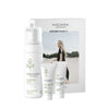MÁDARA-ihonhoitosetti, sisältäen Purifying Foam-, Deep Moisture Fluid- ja Regenerating Cream -tuotteet, aseteltu pystyyn pahvirasian eteen. Astiat ovat valkoisia ja lieriömäisiä mattapinnalla ja minimalistisin mustin pääteviivattomin tekstein. Pakkauksessa on kuva mustapukuisesta naisesta seisomassa hiekkarannalla pilvisen taivaan alla.