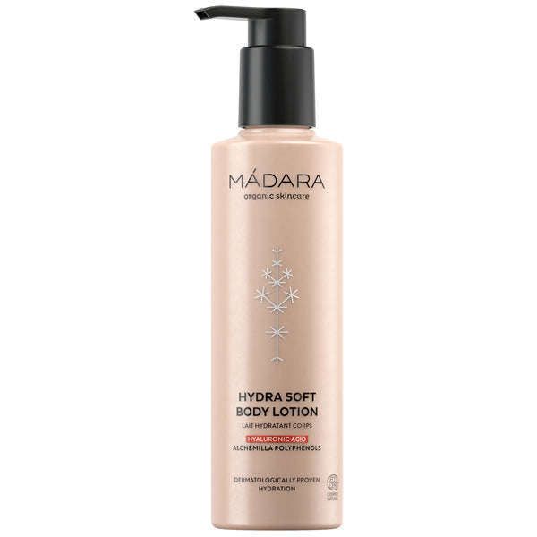 Madara Hydra Soft Vartalovoide; pullo Mádara Hydra Soft Body Lotion -vartalovoidetta pumppuannostelijalla; pullo sylinterinmuotoinen mattapinnalla ja vaaleanbeige, mustalla groteskityyppografialla etiketissä; ainesosia ja ominaisuuksia kuten hyaluronihappoa, alkemillan polyfenoleja ja dermatologisesti todistettua kosteutusta mainitaan; pelkistetty valkoinen tausta, ei ihmisiä tai rekvisiittaa kuvassa.