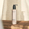 Madara Hydra Soft Vartalovoide; pullo MÁDARA Hydra Soft Body Lotion -vartalovoidetta mustalla pumpulla, pystyssä vaalealla puisella pinnalla; pullo sylinterinmuotoinen mattapinnalla, lihavoitu groteskityyppografia päätekstille; tausta pelkistetty ja neutraali; pehmeä auringonvalo luo varjoja yhdeltä puolelta; ei ihmisiä tai käsiä kuvassa.