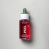 A red glass dropper bottle of MÁDARA PEEL Hyaluron Intense Peel Serum with a green cap, featuring hydrating hyaluronic acid, photographed against a plain light gray background. The bottle is cylindrical with smooth, glossy surfaces and a reflective finish. White sans-serif text appears on the label, which includes the product and brand name in all caps. No people or hands visible.