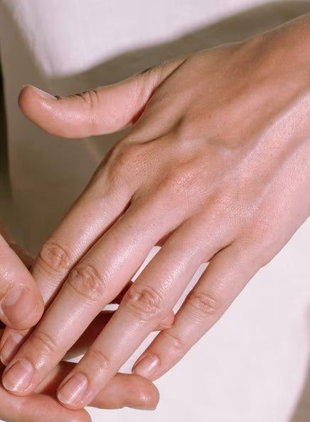 A close-up of a person’s hands with clean, natural nails gently resting on each other against a light background, highlighting well-groomed fingertips. No visible objects, labels, or packaging. Nails are short and smooth with no polish. Background is plain and evenly lit. Only hands are in the frame; no other products or text present.
