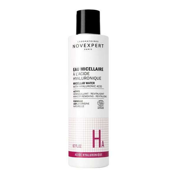 Novexpert HYALURONIC Micellar Water; valkoinen pullo läppäkorkilla, etiketti musta ja vaaleanpunainen kertoen hyaluronihaposta sekä hellävaraisesta puhdistuksesta ja kosteutuksesta; pullo sylinterinmuotoista muovia mattapintaisena; musta suorakulmainen etiketti lihavoidulla groteskikirjasimella, vaaleanpunaista tehosteväriä; valkoinen tausta, ei ihmisiä tai käsiä, suoraan edestä kuvattu.