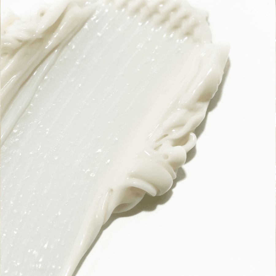 Novexpert OMEGA Rich Protective Cream; lähikuva tekstuurisesta valkoisesta voiteesta tai emulsiosta tasaisesti levitettynä valkoiselle pinnalle, reunoilla näkyvin harjanteineen ja pyörrekuvioineen; tuote puolipaksua ja opaakkia, hienovaraisen kiiltävää pintaa ja näkyvää tekstuuria; ei pakkausta, etikettejä, typografiaa, ihmisiä tai toimintaa kuvassa; tausta yhtenäisen valkoinen.