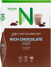 NutriLettt Rich Chocolate Shake box, rectangular with a matte surface and brown color scheme. Product shows chocolate pieces and a glass containing a brown liquid. Main label text: Very Low Calorie Diet, Rich Chocolate Flavoured Shake, All you need in a meal. Sans-serif lettering dominates the packaging. No people or hands present; plain background; front-facing product shot.