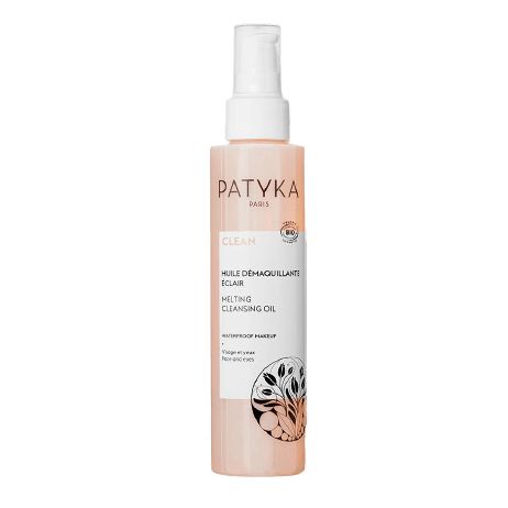 Patyka Paris Clean Melting Cleansing Oil -pullo, valkoinen pumppuannostelija, vaaleanpersikanvärinen suorakulmainen etiketti ja ohut musta kasviaiheinen kuvitus alareunassa; pullo sylinterimäinen ja läpinäkyvä kiiltäväpinnalla; serif-fonttia käytetty päätuotenimessä; tausta valkoinen ja yksinkertainen, ei ihmisiä tai rekvisiittaa näkyvissä.