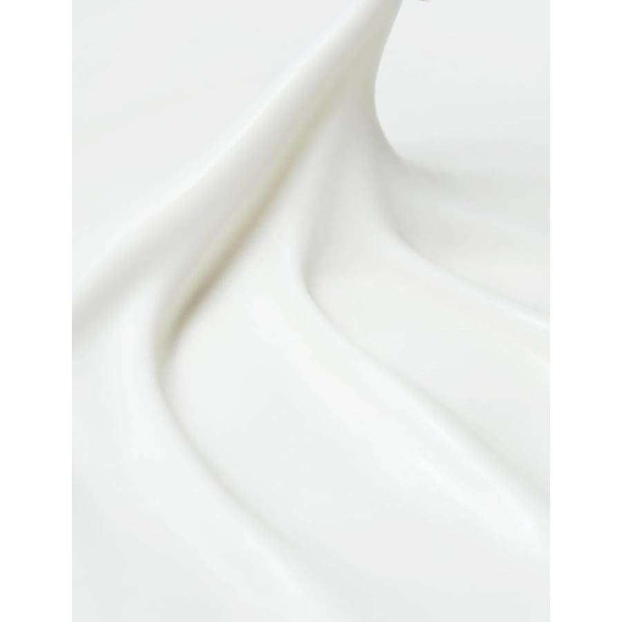 Sileää valkoista voidetta tai emulsiota pehmein virtaavin muodoin ja loivin kaarin, luoden abstraktin, kosteuttavan ja silkkisen ulkonäön; ei näkyvää säiliötä tai pakkausta; pinta hieman kiiltäväpintainen; ei etikettitekstiä, typografiaa, ihmisiä tai käsiä näkyvissä; tausta yksinkertainen ja siisti; lähikuva keskittyy tuotteen tekstuuriin ja muotoon.