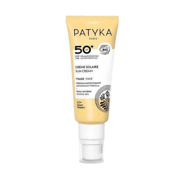 Patyka Face Sun Cream SPF50+ Aurinkovoide kasvoille; tuubi Patyka Paris SPF 50+ -aurinkovoidetta herkälle iholle, valkoisen ja keltaisen suunnittelun kera pumppuannostelijalla; pakkaus mattapintainen; musta ja keltainen teksti etiketissä lukee "SPF 50+" ja viittaa antioksidanttikoostumukseen sekä valtamerten kunnioittamiseen; ei ihmisiä kuvassa; tuote kuvattu vaaleaa taustaa vasten.