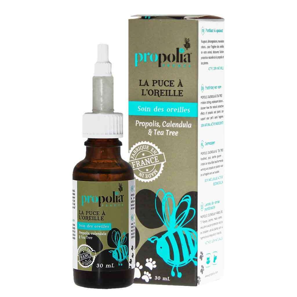 Propolia Ear Care Korvienhoitoneste lemmikille; 30 ml pullo Propolia La Puce à l'Oreille -korvienhoitonestettä pakkauksen kera, molemmat mattapintaisia; etiketissä ja pakkauksessa suuri sininen mehiläiskuvitus, seka- ja isoaakkosin typografia sekä ainesosamaininnat propoliksesta, kehäkukasta ja teepuusta; tuotenimi näkyvissä; valkoinen tausta, ei ihmisiä tai käsiä kuvassa.