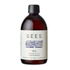 A brown bottle with a black cap labeled SEES No2 Rauhoittava, featuring a calming lavender & peppermint scent, described as laundry vinegar. The label features blue horizontal lines and text in multiple languages. The surface of the bottle is matte. The typography is mainly sans-serif and clean. Background is plain light grey with no objects or distractions, shot is front-facing product-only at mid-range distance. No people or hands are visible in the image.