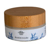 A round jar with a wooden lid labeled Sinkkivoide, featuring soothing blue grass-like illustrations and the Saaren Taika logo for a touch of natural elegance. The jar is white with a matte finish and has clear blue printed graphics and sans-serif text. The lid is light-colored wood with visible grain. The photo shows only the product against a plain white background, no people or props are present.