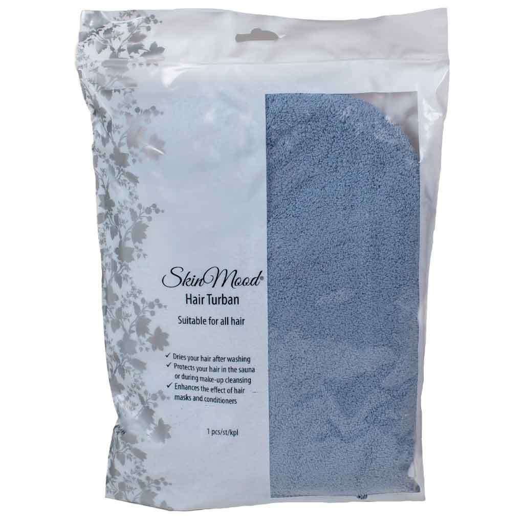 SkinMood Hair Turban Hiusturbaani; vaaleansininen pakattu hiusturbaani nopeaan ja hellävaraiseen hiustenkuivaukseen; pakkaus suorakulmainen mattapintainen, läpinäkyvä ikkuna näyttää tuotteen; etupuolella musta groteskiteksti hyödyistä sekä vaaleanpunaisia ja vihreitä kukkakuvioita valkoisella taustalla; ei ihmisiä kuvassa, tasainen studiovalaistus.