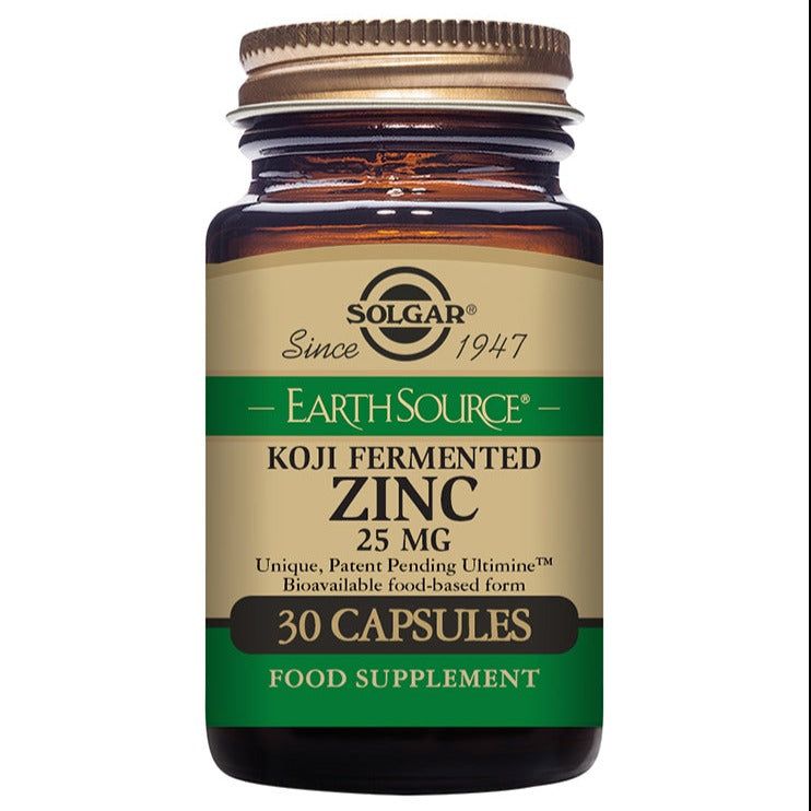 A bottle of Solgar Earth Source Koji Fermented Zinc 25 mg, containing 30 capsules. The brown glass bottle has a gold screw cap and a matte finish. The label features serif and sans-serif fonts in green, black, and gold on a beige background. Visible text indicates it is a food supplement and mentions bioavailable, food-based zinc for daily wellness support. The product sits against a plain white background with no people or hands visible.