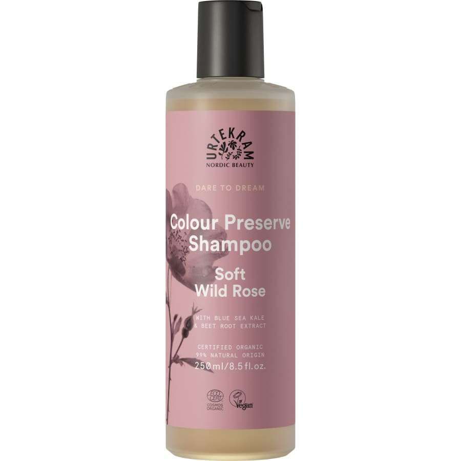 Urtekram Dare to Dream Soft Wild Rose Shampoo; pullo tekstillä "Urtekram Colour Preserve Shampoo, Soft Wild Rose"; muovipullo lieriömäinen mattavaaleanpunaisella etiketillä ja kukkakuvituksin; etikettitekstissä mainitaan sinilevä, punajuuriuute, vegaanisertifiointi ja koko 250 ml; groteskifontteja käytössä; ei ihmisiä tai lisäesineitä; tausta yksinkertainen.