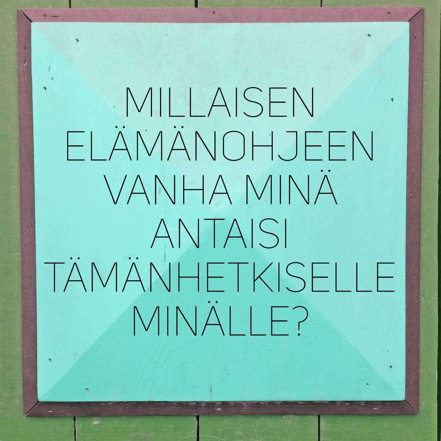 Hidasta Elämää Voimauttavat Kysymykset -kortit; turkoosi neliönmuotoinen kyltti tasaisesta mattamateriaalista kiinnitettynä yhtenäiselle vihreälle seinälle; pinnalla keskitettyä suomenkielistä tekstiä yksinkertaisella groteskifontilla; ei grafiikoita, logoja tai koristeita kyltissä; ei pakkausta tai kehystä näkyvissä; ei ihmisiä tai käsiä kuvassa; kyltti kehottaa pohtimaan, mitä neuvoja oma vanhempi itsensä antaisi nykyiselle itselle.