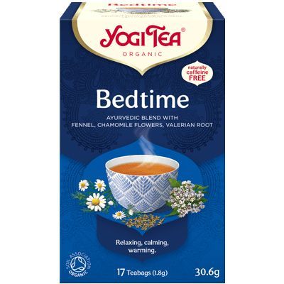 YogiTea Luomu Bedtime -teepakkaus; kuvassa teekuppi ja kamomillankukkia; suorakulmainen pahvipakkaus mattapinnalla, pääväri sininen ja keltainen; luettavassa etiketissä teksti "Ayurvedic blend", "naturally caffeine free", "17 teabags"; serif-fontti tuotenimessä, tekstausvapaata fonttia yksityiskohdissa; tausta valkoinen; ei ihmisiä tai käsiä näkyvissä; kuva otettu edestä silmän tasolta.