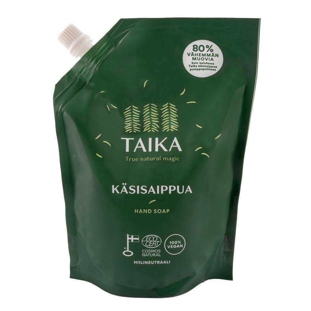 Taika Käsisaippua; vihreä Taika-käsisaippuan täyttöpussi ekomerkinnöin, valkoinen korkki vasemmassa yläkulmassa, teksti suomeksi ja englanniksi; pussi mattapintaista joustavaa muovia; lihavoitua groteskitypografiaa pääetiketeissä; vaalea tausta, ei ihmisiä tai käsiä lähikuvassa.