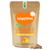 Together Health Vitamin C; ruskea joustava pussi mattapintaisena pystyssä, teksti "Together Vitamin C with Bioflavonoids Whole Food Supplement" selkeällä groteskikirjasimella; keskellä oranssi sydämenmuotoinen logo; kaksi beigeä vegaanikapselia pussin vieressä vaalealla alustalla; yksinkertainen tuotekuva, ei ihmisiä kuvassa.