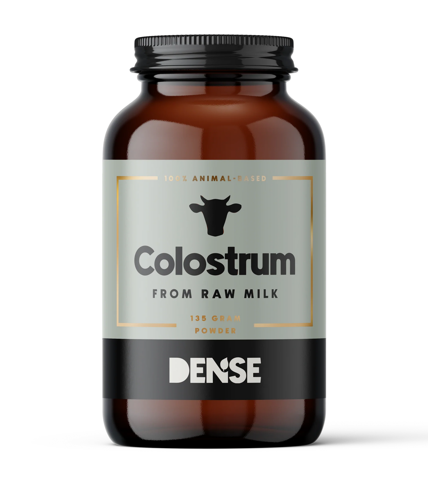 DENSE Ternimaitojauhe; ruskea lasipurkki tekstillä "Colostrum from Raw Milk", 135 g jauhetta, tiivis kaava; musta lehmäkuvake ja kultaiset korostukset; lieriön muotoinen purkki kiiltäväpintaisena tummansävyisellä kierrekannella; selkeä musta-kultainen groteskiteksti; valkoinen tausta, ei ihmisiä tai tarvikkeita, tuote keskitettynä kuvassa.