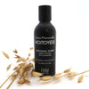 Fiini Naturally Kaura-Kamomilla Hoitovesi; musta pullo tekstillä "Hoitovesi Nurturing Toner" ympäröitynä kaurantähkillä valkoisella taustalla; pullo mattapintainen ja sylinterinmuotoinen; etiketissä selkeä groteskiteksti; kaurantähkät kuivia ja vaaleita näkyvin siemenpäin; ei ihmisiä tai käsiä kuvassa.