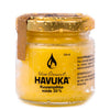 Havuka Kuusenpihkavoide 30% -lasipurkki, metallinen kultainen kierrekansi, molemmat peittyneenä näkyvin vesipisaroin; purkki sylinterimäinen ja läpinäkyvä, sisällä näkyy keltaista voidetta; etiketissä mustaa tekstausvapaata tekstiä ja puunpihkapisarasymboli; tausta yksinkertainen ja epätarkka; ei ihmisiä tai käsiä näkyvissä kuvassa.