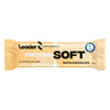 Leader Performance Protein Soft Valkosuklaa; beige ja valkoinen proteiinipatukan käärepaperi tekstillä "Leader Performance Protein Soft White Chocolate, 60 g"; pakkaus korostaa 20 g proteiinia, 18 g kuitua, gluteenittomuutta, ei sokerialkoholeja, sekä sinistä sertifiointimerkkiä; mattapintainen lihavoitu groteskiteksti mustin ja kultaisin sävyin; suorakulmainen rypytetyin reunoin; lähikuva vaalealla taustalla, ei ihmisiä kuvassa.