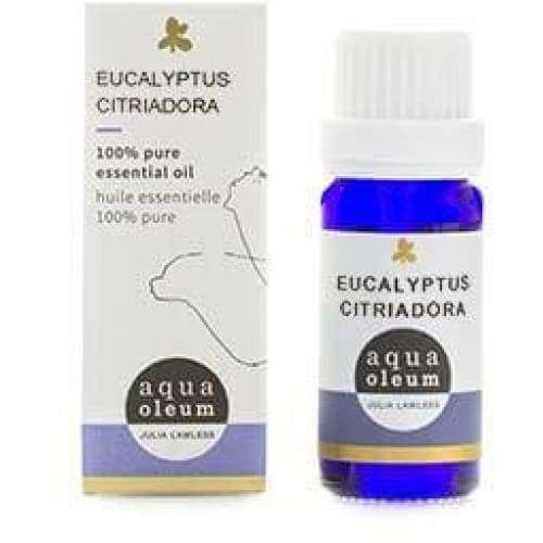 Sininen lasipullo merkinnällä Eucalyptus Citriodora essential oil seisoo pystyssä valkoisen suorakulmaisen rasian vieressä. Rasiassa on minimalistinen musta viivakuvitus eukalyptuksen lehdistä ja yksinkertainen pääteviivaton typografia. Sekä pullo että rasia ovat mattapintaisia. Esineet on aseteltu pelkistetylle vaalealle taustalle, eikä kuvassa näy ihmisiä tai käsiä.