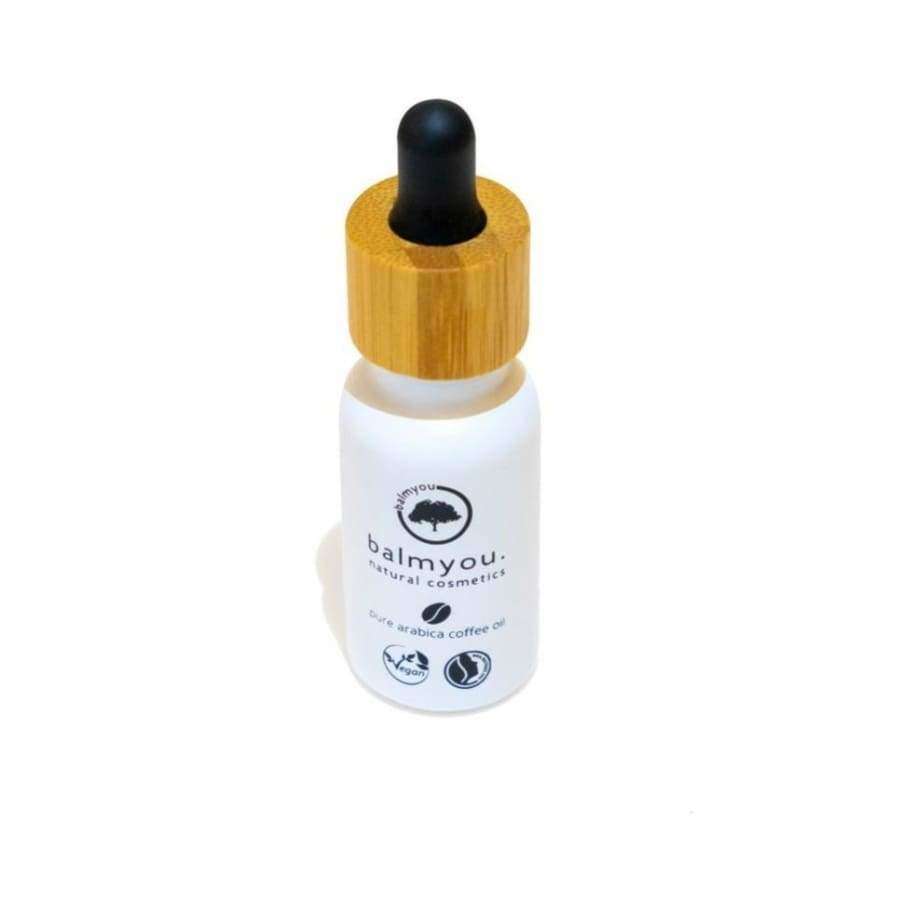 balmyou. natural cosmetics pure arabica coffee oil -pullo; pieni valkoinen tippapullo puisella korkilla, pystyssä sileällä valkoisella taustalla; pullo mattapintainen ja sylinterimäinen; etikettiteksti pienaakkosin tekstausvapaalla fontilla mustana; ei ihmisiä tai esineitä näkyvissä.