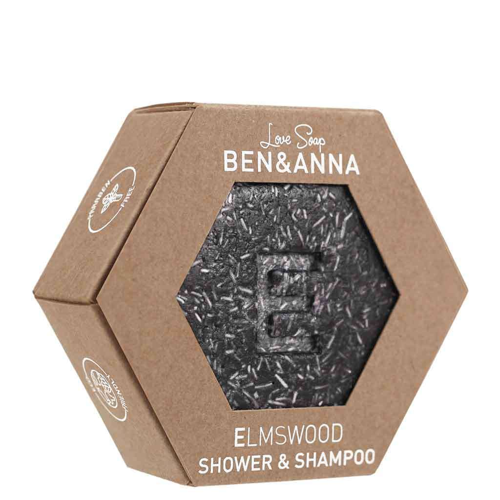 Ben & Anna Shower & Shampoo palasaippua Elm Wood; kuusikulmainen, ruskea ja mattapintainen pahvipakkaus, jossa tumma ja tekstuurinen pyöreä shampoosaippua kirjaimella "E" päällä; valkoinen groteskiteksti; vaalea tausta.