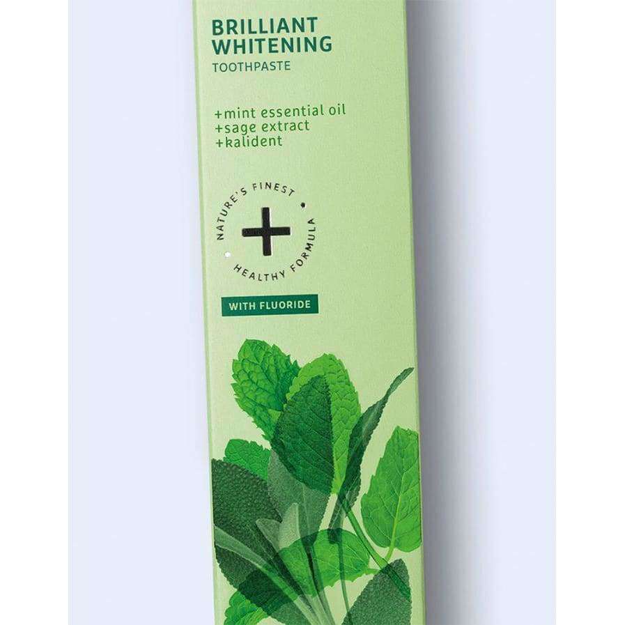 Ecodenta Brilliant Whitening Valkaiseva Fluorihammastahna; vihreä pahvirasia hammastahnaa, suorakulmainen ja mattapintainen, teksti "Brilliant Whitening" näkyvästi groteskikirjaimin; etuosassa minttulehtikuvituksia; ainesosaluettelossa mainittu minttueteerinen öljy, salviauute, Raídent ja fluori; tuote kuvattu vaalealla taustalla.