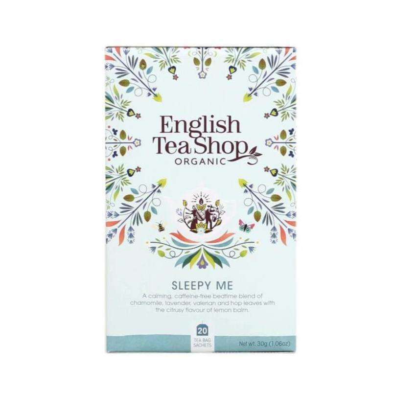 English Tea Shop Luomu Sleepy Me -teepakkaus; suorakulmainen ja mattapintainen rasia, pääosin sininen; etupaneelissa koristeellisia kukkakuvioita; teksti kuvailee tuotteen rauhoittavaksi ja kofeiinittomaksi yrttiseokseksi iltateeksi; tuotenimi ja kuvaus pääte- ja tekstausvapaalla kirjasimella; kuvattu silmän korkeudelta valkoista taustaa vasten, näkyvissä vain rasian etupuoli, ei ihmisiä.