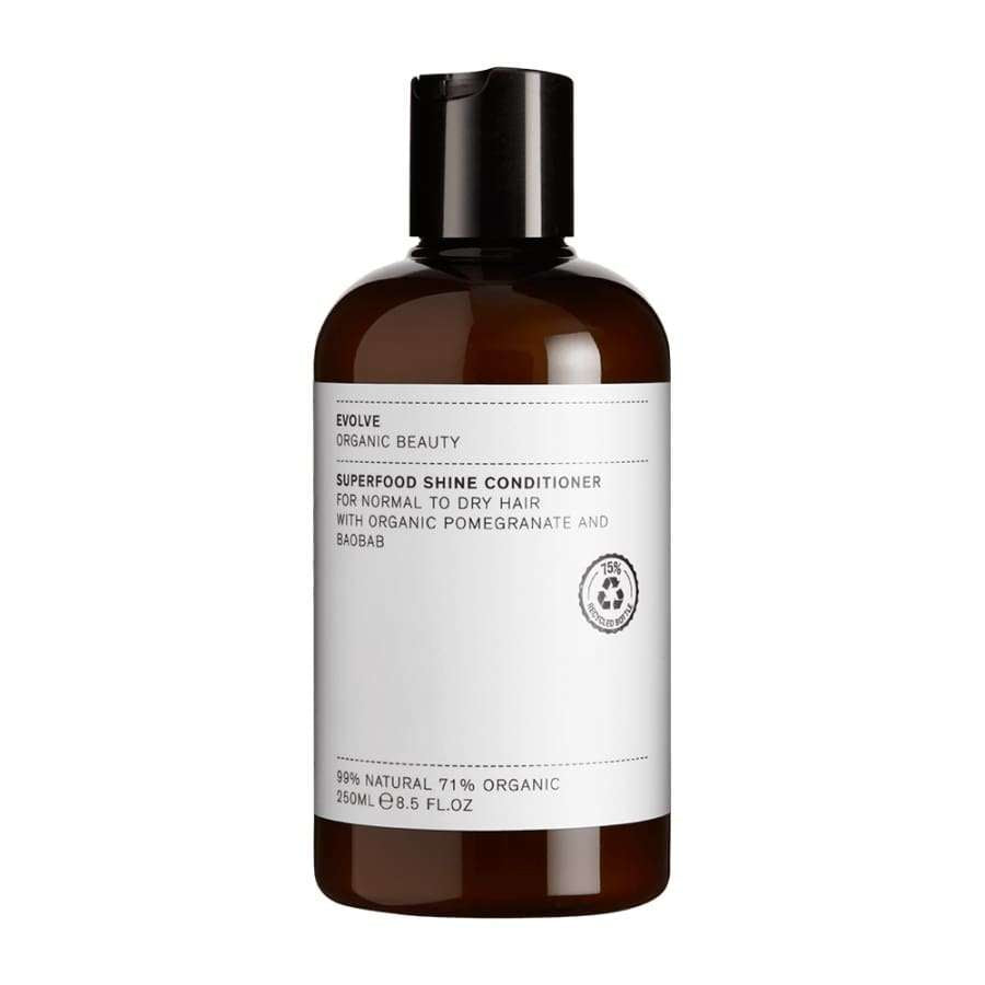 Evolve Superfood Shine Hoitoaine -pullo, 250 ml; ruskea, sylinterimäinen ja kiiltäväpintainen muovipullo mustalla kierrekorkilla; valkoisessa suorakulmaisessa etiketissä pääte- ja tekstausvapaata tekstiä tuotteen soveltuvuudesta normaalille ja kuivalle hiukselle sekä sisällöstä, kuten granaattiomena- ja baobabiöljystä; kuvattu yksiväristä taustaa vasten, ei ihmisiä tai käsiä näkyvissä.