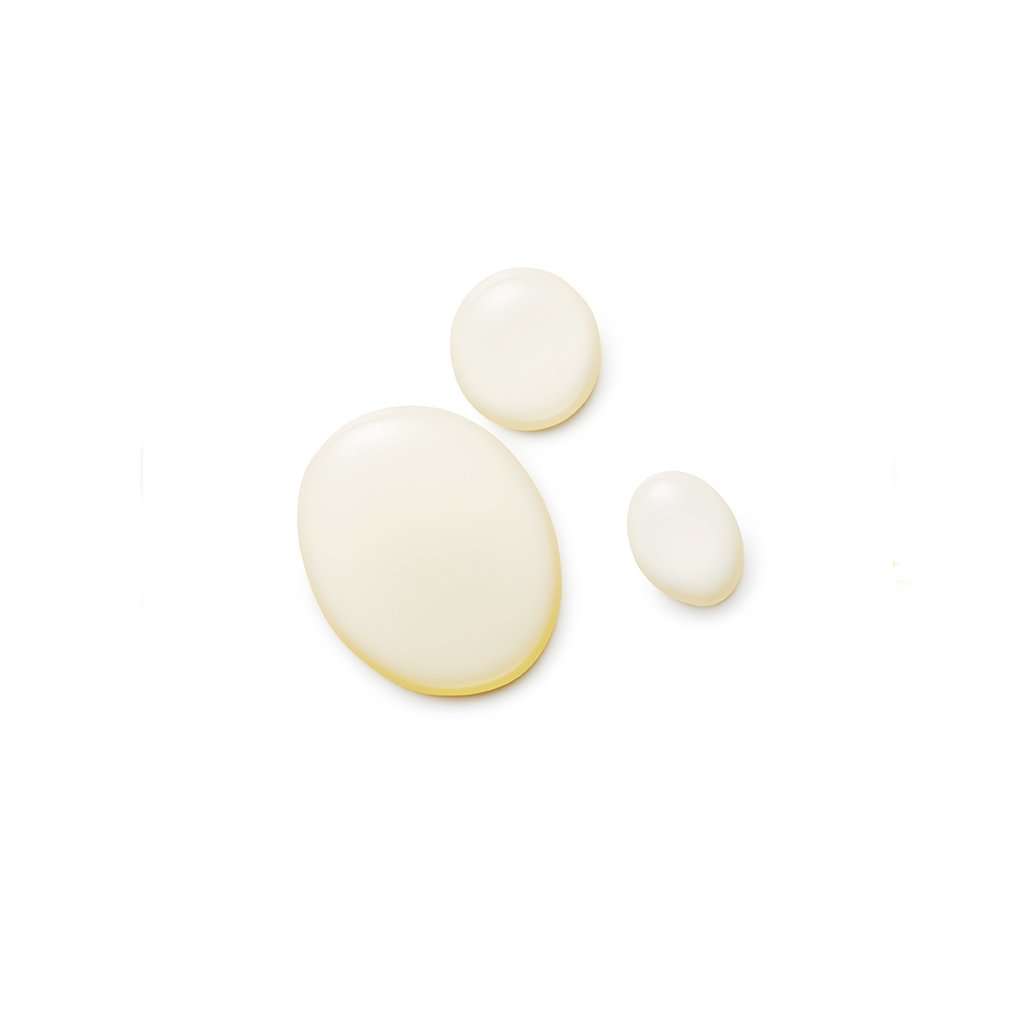 Kolme vaaleaa, kermaista emulsiopisaraa eri kokoisina valkoisella taustalla, suurimmasta pienimpään; pinta läpikuultamaton ja sileä; ei pakkausta tai etikettiä näkyvissä; ei ihmisiä tai käsiä; kuvattu ylhäältä päin keskittyen vain tuotteeseen.