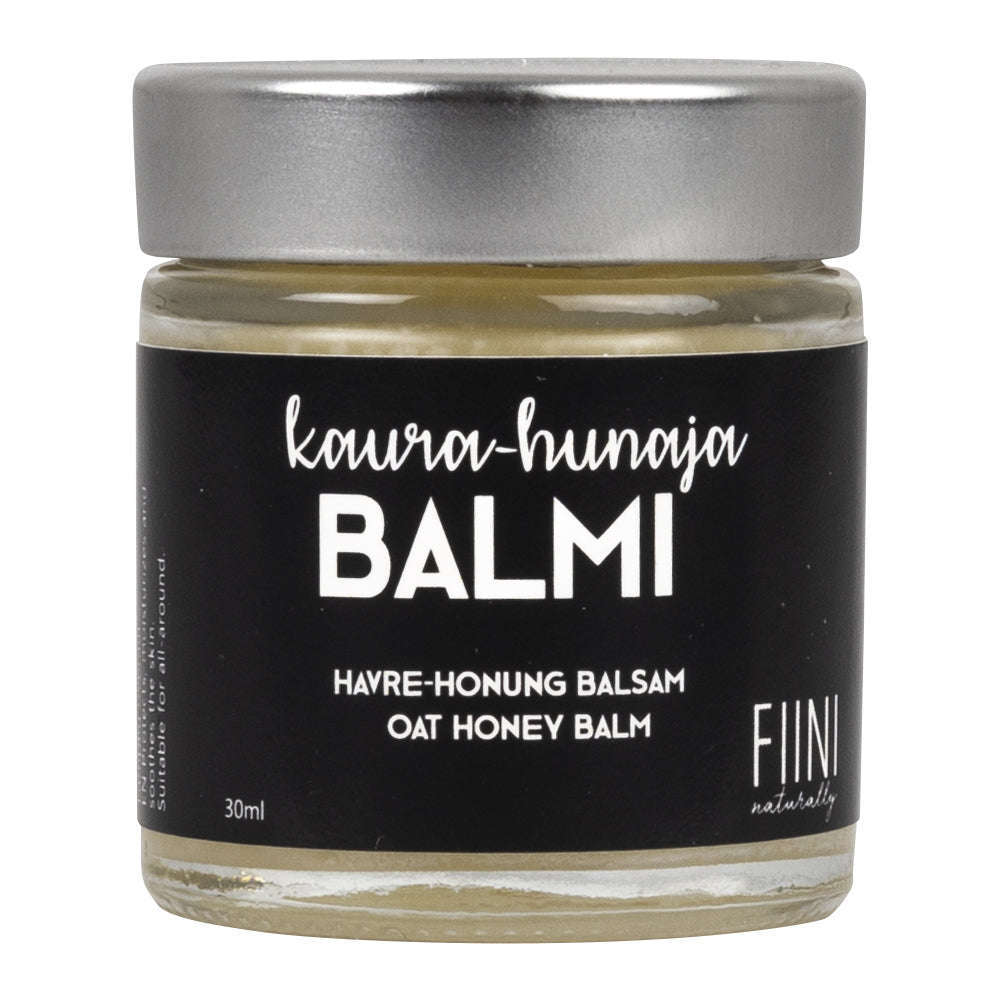 Fiini Naturally Kaura-Hunaja Voide, 30 ml; pieni lasipurkki heijastavalla hopeisella kannella; musta mattapintainen etiketti valkoisella groteskitekstillä "Kaurahunaja Balmi (Oat Honey Balm) by FIINI naturally"; vaalea tausta, suora yksinkertainen tuotekuva ilman ihmisiä tai käsiä.