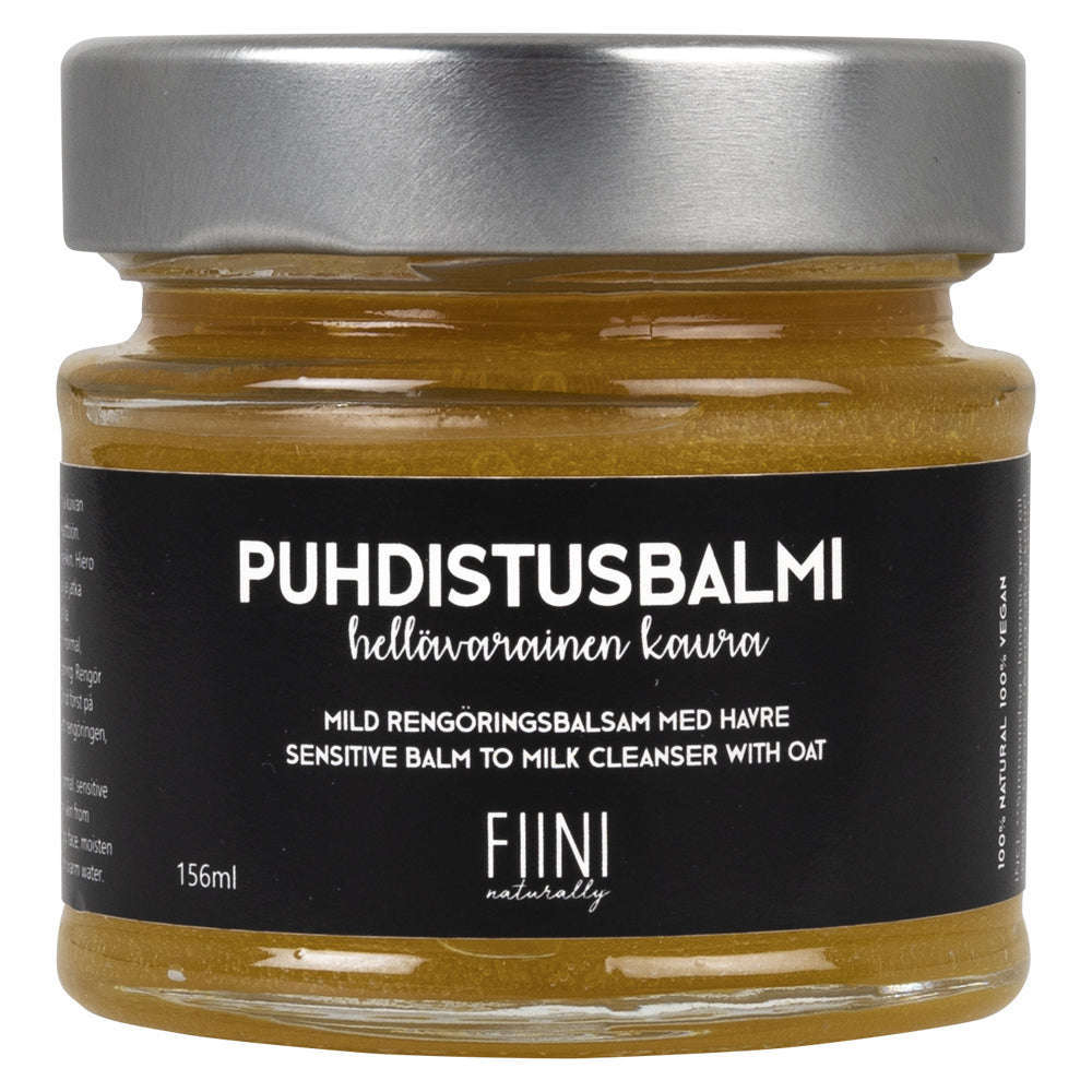Fiini Naturally Puhdistusbalmi Hellävarainen Kaura, 156 ml; lasipurkki mustalla etiketillä, teksti valkoisella ja beigellä suomeksi, ruotsiksi ja englanniksi; sisällä kultaisenkeltainen hoitava balmi; purkki leveä ja sylinterinmuotoinen, mattapintainen, suorat reunat ja tasainen pohja; kansi metallinen ja mattapintainen; neutraali tausta ilman ihmisiä tai käsiä.