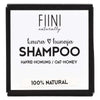 Fiini Naturally Kaura-Hunaja Shampoopala; neliönmuotoinen pakkaus, tekstinä "FIINI naturally", "Kaur & hunaja SHAMPOO" ja "Havre-Honung / Oat-Honey", alaosan raidassa lukee "100% NATURAL"; pakkaus vaalea kartonki mattapintaisena; groteskikirjasin eri painoin; vaalea tausta, ei ihmisiä tai käsiä kuvassa.
