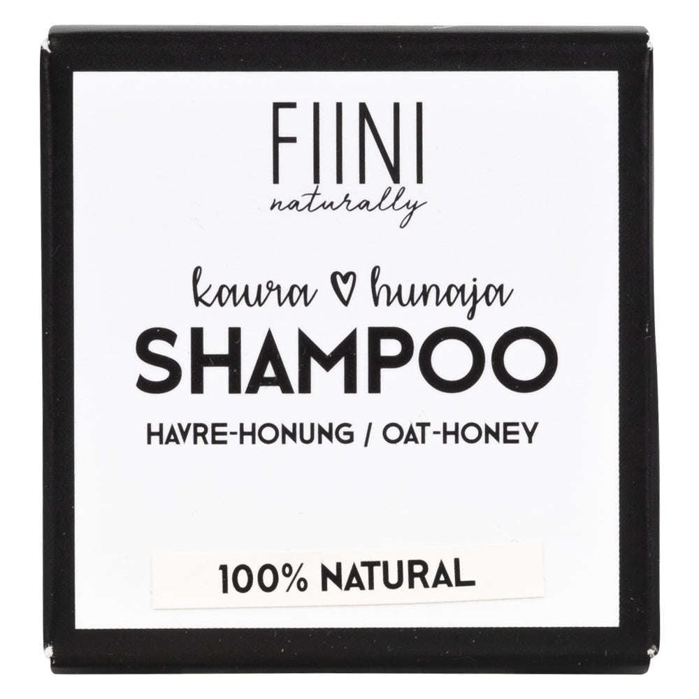 Fiini Naturally Kaura-Hunaja Shampoopala; neliönmuotoinen pakkaus, tekstinä "FIINI naturally", "Kaur & hunaja SHAMPOO" ja "Havre-Honung / Oat-Honey", alaosan raidassa lukee "100% NATURAL"; pakkaus vaalea kartonki mattapintaisena; groteskikirjasin eri painoin; vaalea tausta, ei ihmisiä tai käsiä kuvassa.