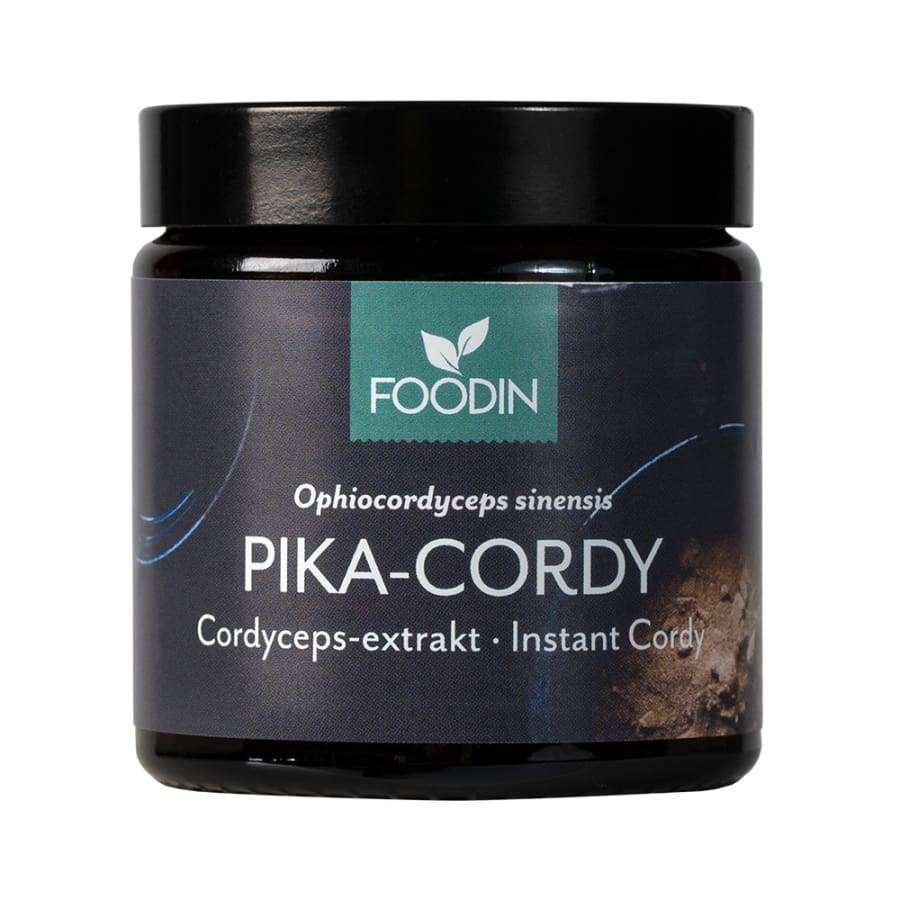 FOODIN PIKA-CORDY; musta, lieriömäinen, mattapintainen purkki; tumma etiketti, jossa vihreä FOODIN-logo, yksinkertaista groteskitekstiä sekä sanat "Cordyceps-extract" ja "Instant Cordy"; pientä tekstiä tuotenimen yläpuolella; vaalea tausta, ei ihmisiä.
