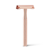 The Original Geisha Shaver -parranajokone; ruusukultainen, tekstuuripintaisella kahvalla, pystyssä vaalealla taustalla; metalli kiiltävä ja sileä, koko esine yhtenäistä materiaalia ja väriä; ei pakkausta tai merkintöjä; ei ihmisiä tai muuta rekvisiittaa; studiokuva pelkästä tuotteesta.